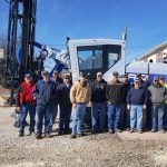 A group of men standing in front of a large crane.