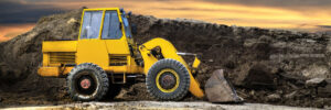 A bulldozer or loader moves the earth at the construction site against the sunset sky. Construction heavy equipment for earthworks