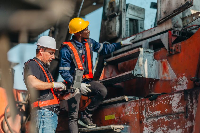 Worker in a hard hat and reflective safety vest inspects machinery